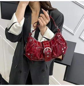 Detail of red crocodile texture handbag with silver rivets and metallic buckle accents