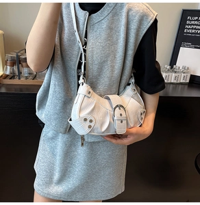 Detailed view of white crocodile pattern half-moon bag with silver rivets on model