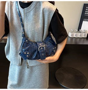 Detail of blue faux crocodile leather bag with silver studs and pin buckle hardware