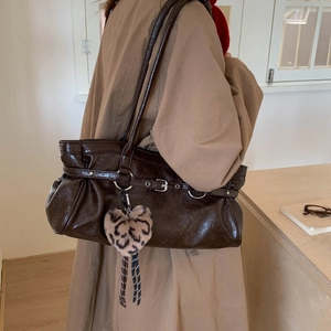 Detail of dark brown glossy tote with crinkled texture, silver buckle and leopard heart charm
