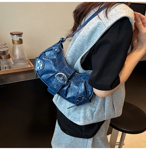 Detail of blue crocodile pattern shoulder bag with silver rivets and buckle decor