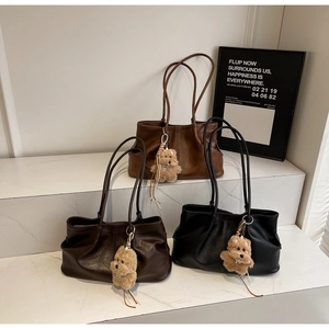 Detailansicht von drei Vintage-Einkaufstaschen in Braun und Schwarz mit Plüschanhängern