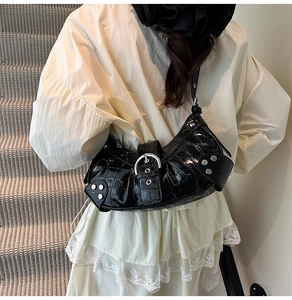 Detail of black crocodile texture handbag with silver rivets and buckle straps
