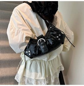Detailed shot of crocodile-patterned underarm bag with silver buckle and studs