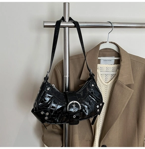 Detail of black crocodile texture shoulder bag with silver rivets and buckle