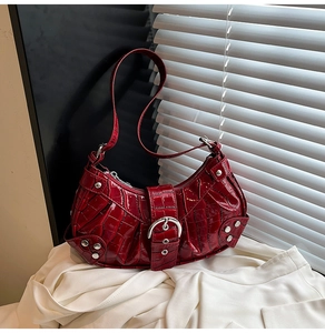 Detail of red crocodile pattern patent leather bag with silver metal buckle and rivets