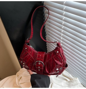 Detail of red crocodile pattern patent leather shoulder bag with silver studs