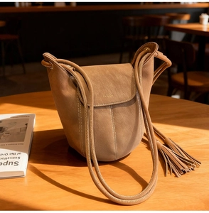Détails d'un sac seau en daim marron clair avec franges et surpiqûres apparentes