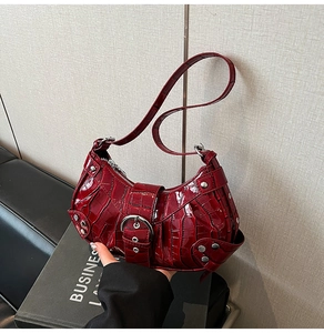 Detail of burgundy crocodile pattern faux leather with silver buckle and metal studs