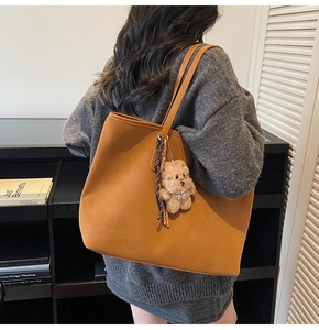 Vista de detalle de un bolso tote grande de cuero marrón llevado por una modelo en estudio