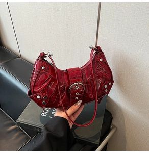 Close-up of red crocodile pattern leather bag with silver rivets and buckle details