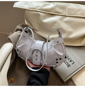 Detail of white crocodile pattern leather bag with silver rivets and large buckle closure