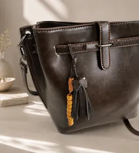 Detail der dunkelbraunen Eimer-Tasche aus Leder mit Quasten und Holzperlen-Dekor