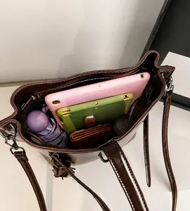 Makroansicht des geräumigen Innenraums der braunen Beuteltasche mit Tablet und Schirm