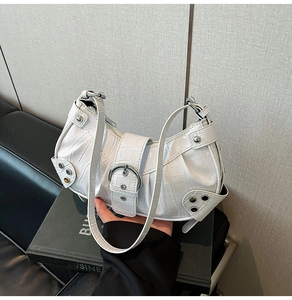 Close-up of white crocodile pattern shoulder bag with silver studs and metal buckle