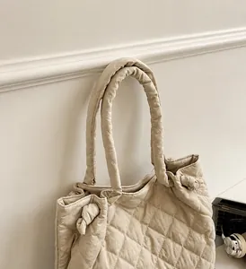 Détail du sac cabas matelassé beige avec surpiqûres en losanges et nœud décoratif