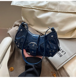 Close-up of deep blue crocodile pattern leather bag with silver rivets and metal hardware