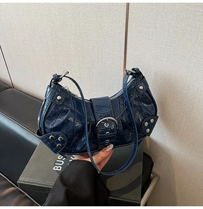 Detail of navy blue patent crocodile embossed leather with silver rivets on crescent bag