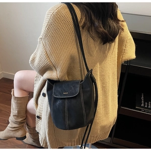 Vue détaillée du sac seau noir avec coutures contrastées et lettrage fashion élégant