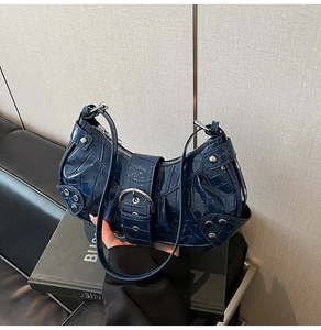 Detailed view of crocodile embossed glossy dark blue leather with silver buckle and studs
