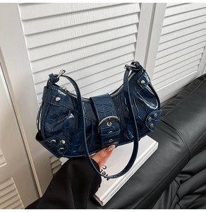 Detail of dark blue crocodile pattern patent leather shoulder bag with silver metal rivets