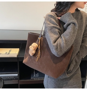 Detalle del bolso tote grande de ante marrón oscuro con un bonito colgante de oso de peluche