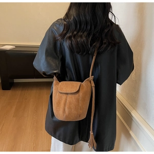 Gros plan du sac seau en daim marron avec franges latérales et gaufrage de mode