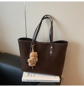 Vista detallada del bolso tote de cuero sintético marrón oscuro con colgante de oso peluche