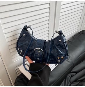 Detail showing deep blue crocodile embossed texture and silver studs on the handbag