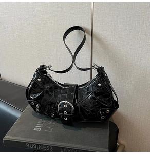Close-up of glossy black crocodile pattern leather bag with silver buckle and rivets