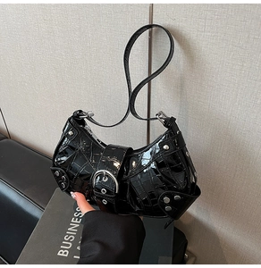 Detail of black crocodile texture patent leather bag with silver rivets and metal buckle