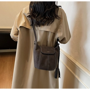 Gros plan d'un sac à bandoulière gris mat avec coutures contrastées et plaque en métal