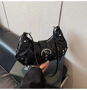 Detail of black glossy crocodile pattern on hobo bag with silver studs and metal hardware