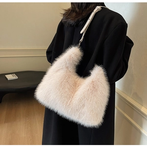 Close-up of fluffy plush bag in beige with slim leather strap on a black coat