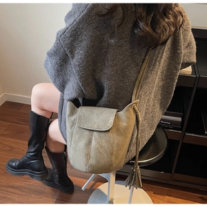 Détail du sac seau vintage vert olive avec cordon à pompons et rabat texturé