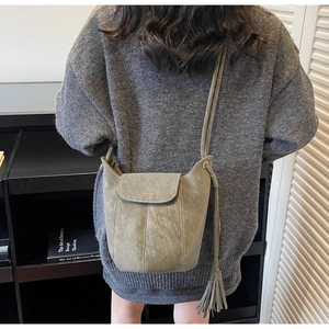 Vue arrière d'un mannequin portant le sac seau bandoulière vert sauge avec des glands