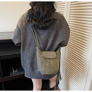 Détail du sac seau vert olive vintage avec logo mode et long pompon à franges en cuir