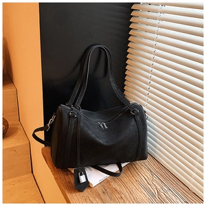 Detailed view of black retro tote bag with silver lock charm on a wooden surface