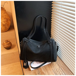 Detail of black suede Boston tote bag showing metal lock and dual zipper closures