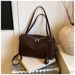 Deep brown matte leather Boston bag detail with metal lock and adjustable shoulder strap