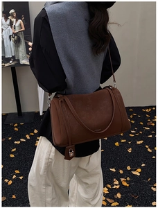 Detail shot of brown matte leather tote bag with silver metal lock and brand logo detail