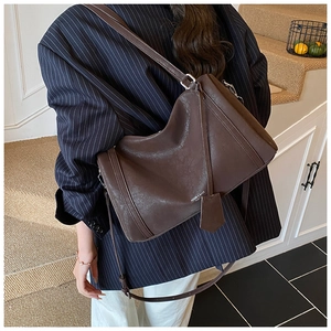 Detail of dark brown leather tote bag with white text logo and stylish long shoulder strap