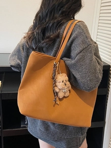Bolso tote marrón minimalista de cuero sintético con colgante de oso llevado al hombro