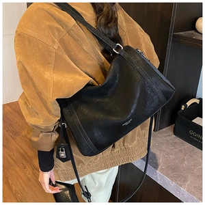 Detailed side view of the black leather tote bag with silver lock charm on a model