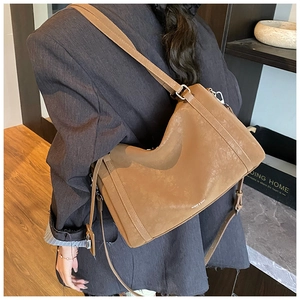 Side view of a brown matte leather shoulder bag with sleek lines and silver metal buckle