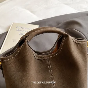 Close-up of suede tote bag showing premium white stitching and matte leather texture