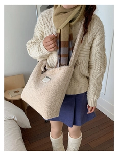 Detail view of the beige plush bucket bag texture with a woven SEEYOU logo label