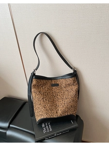 Dettaglio della borsa a secchiello leopardata con bordi in pelle nera e logo in metallo