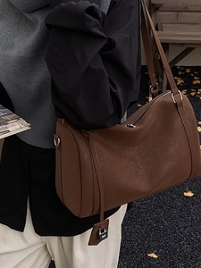 Vintage dark brown leather Boston bag with a matte finish and top handle on a bench