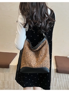 Dettaglio borsa hobo leopardata con tracolla in pelle nera indossata da una modella